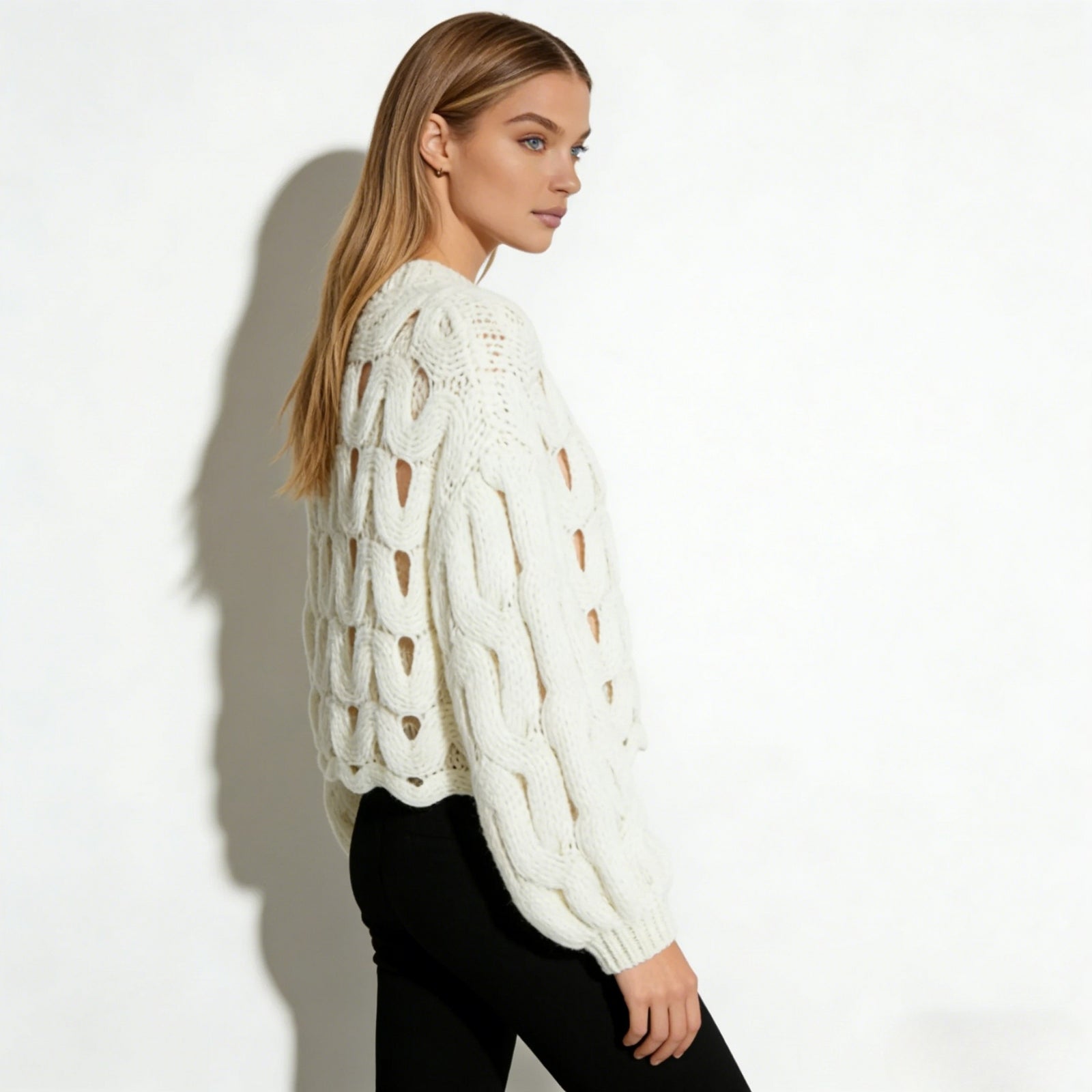 Side profile of a model in the Kouvr Fashion white cutout chunky knit sweater, highlighting the voluminous balloon sleeve and open-weave detail.