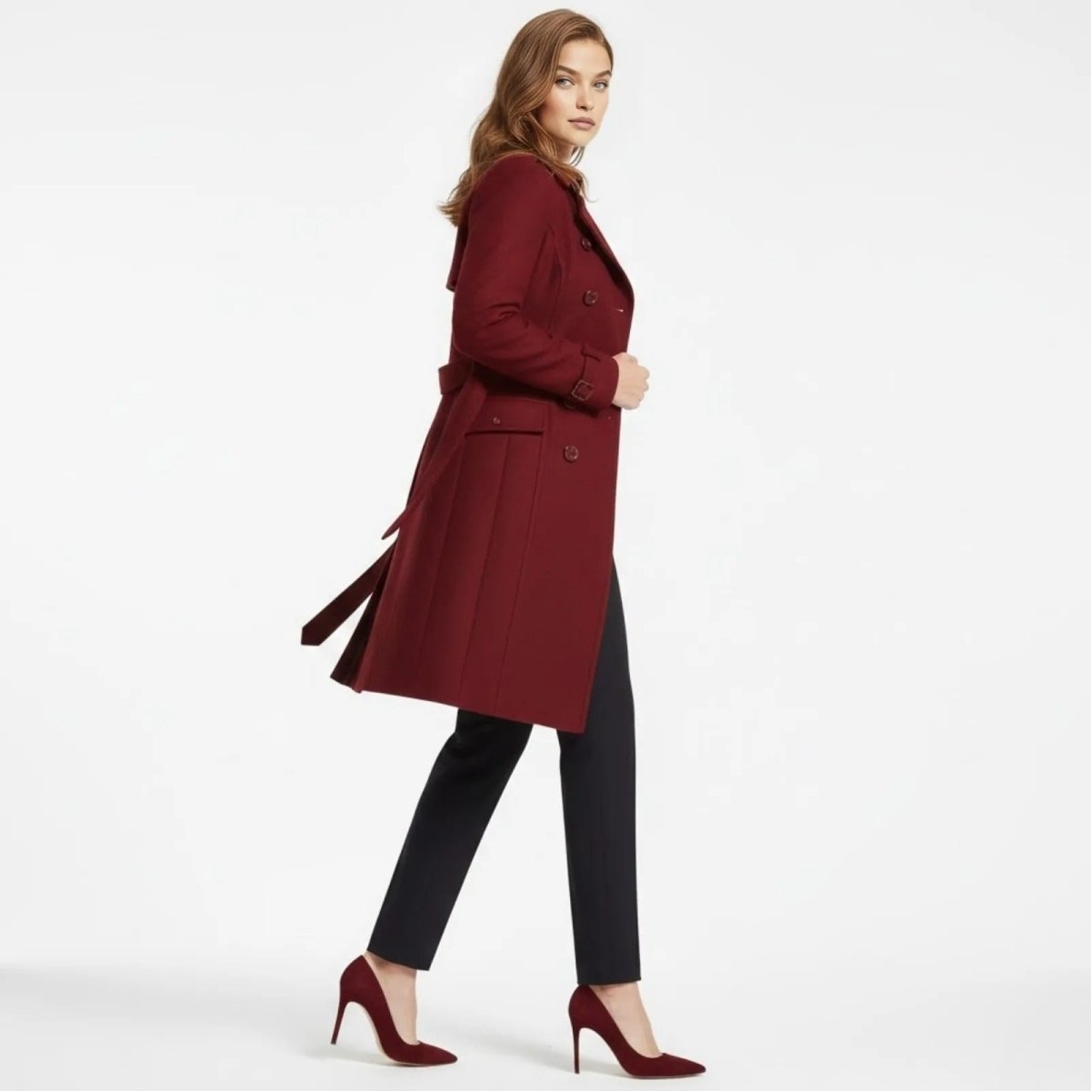 Side profile of a woman walking in the Kouvr Fashion red wool trench coat, showing the belted waist and fluid movement of the garment.