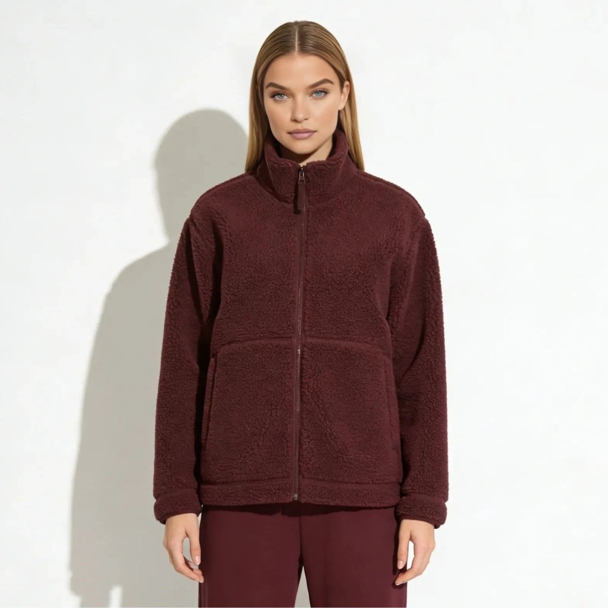 Woman with blonde hair wearing the Kouvr Fashion luxury burgundy sherpa fleece jacket with a high collar, shown from the front against a white background.