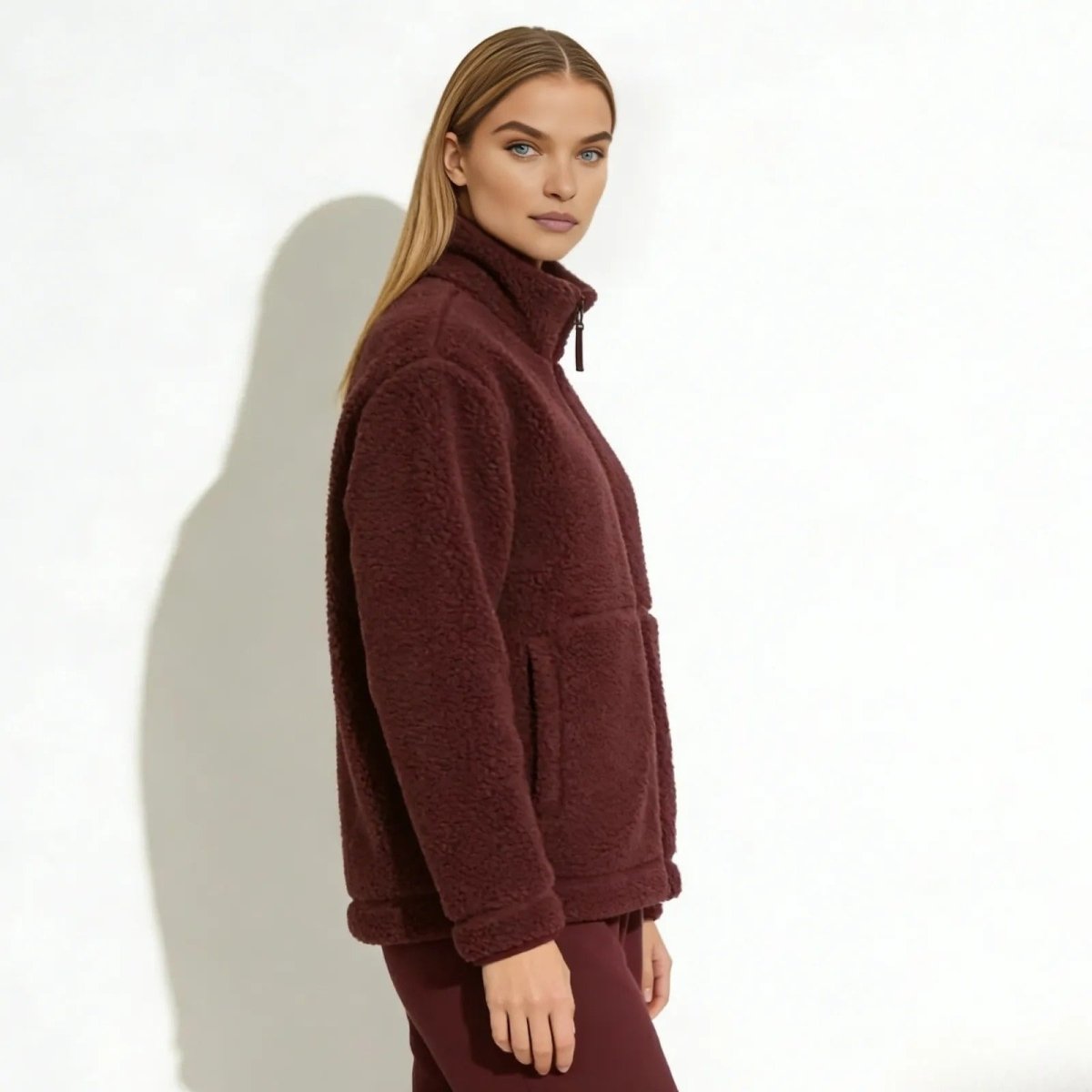 Side profile of a woman wearing the Kouvr Fashion high-collar burgundy teddy jacket to show its fit and texture.