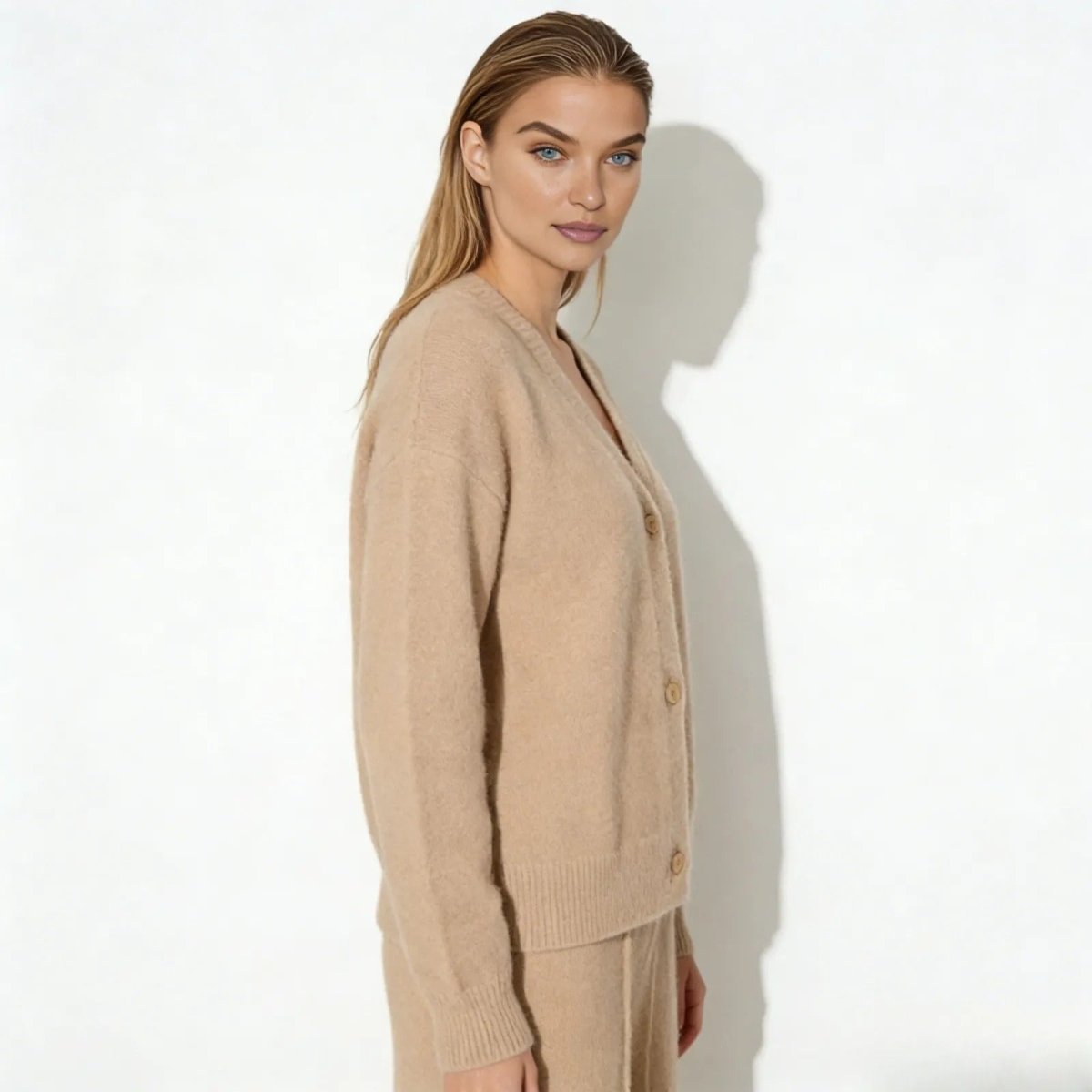 Side profile of a woman wearing a relaxed fit beige cashmere cardigan from Kouvr Fashion, showing the drape of the sleeve.