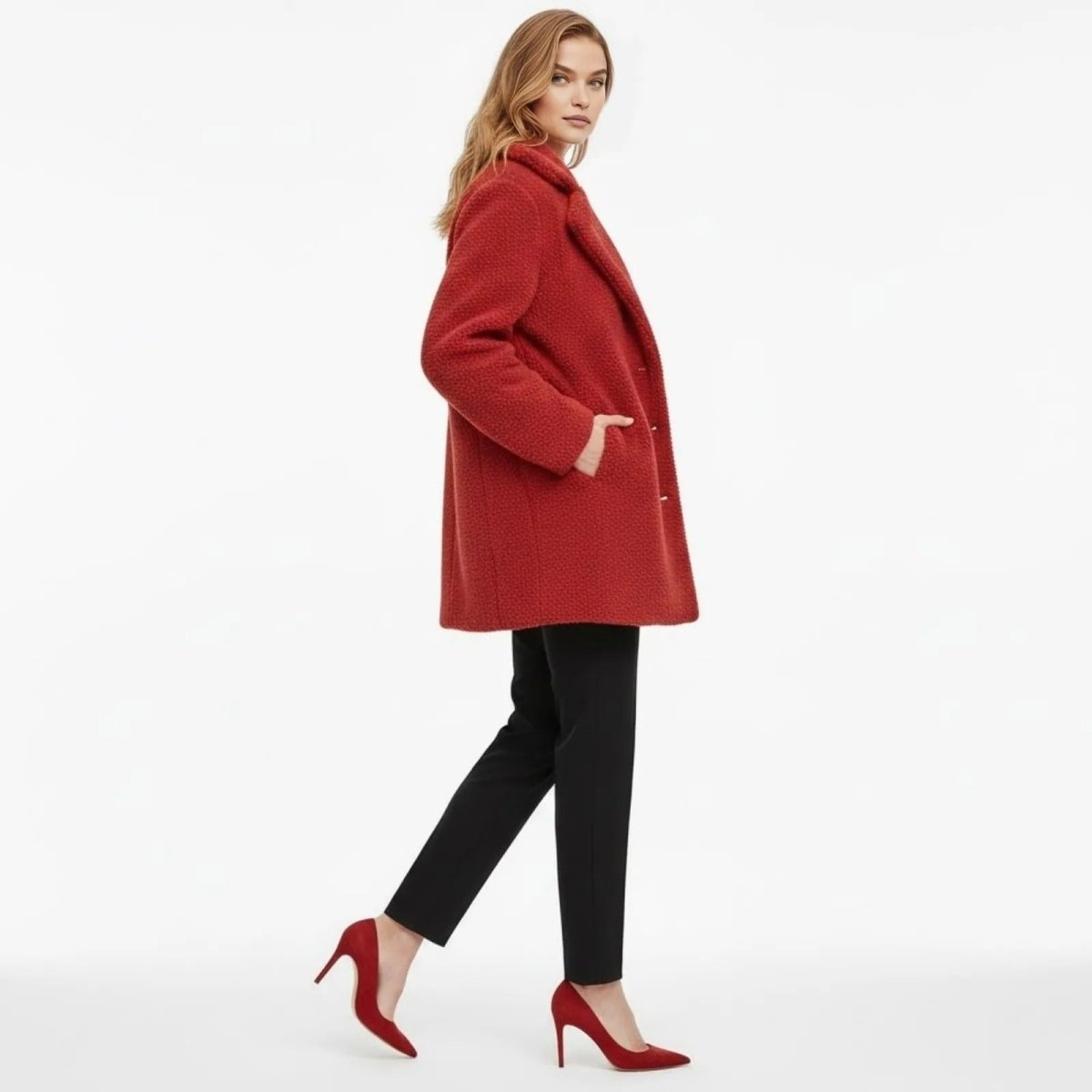 Side view of a woman walking in a red oversized sherpa coat by Kouvr Fashion, showcasing its mid-length cut and relaxed silhouette.