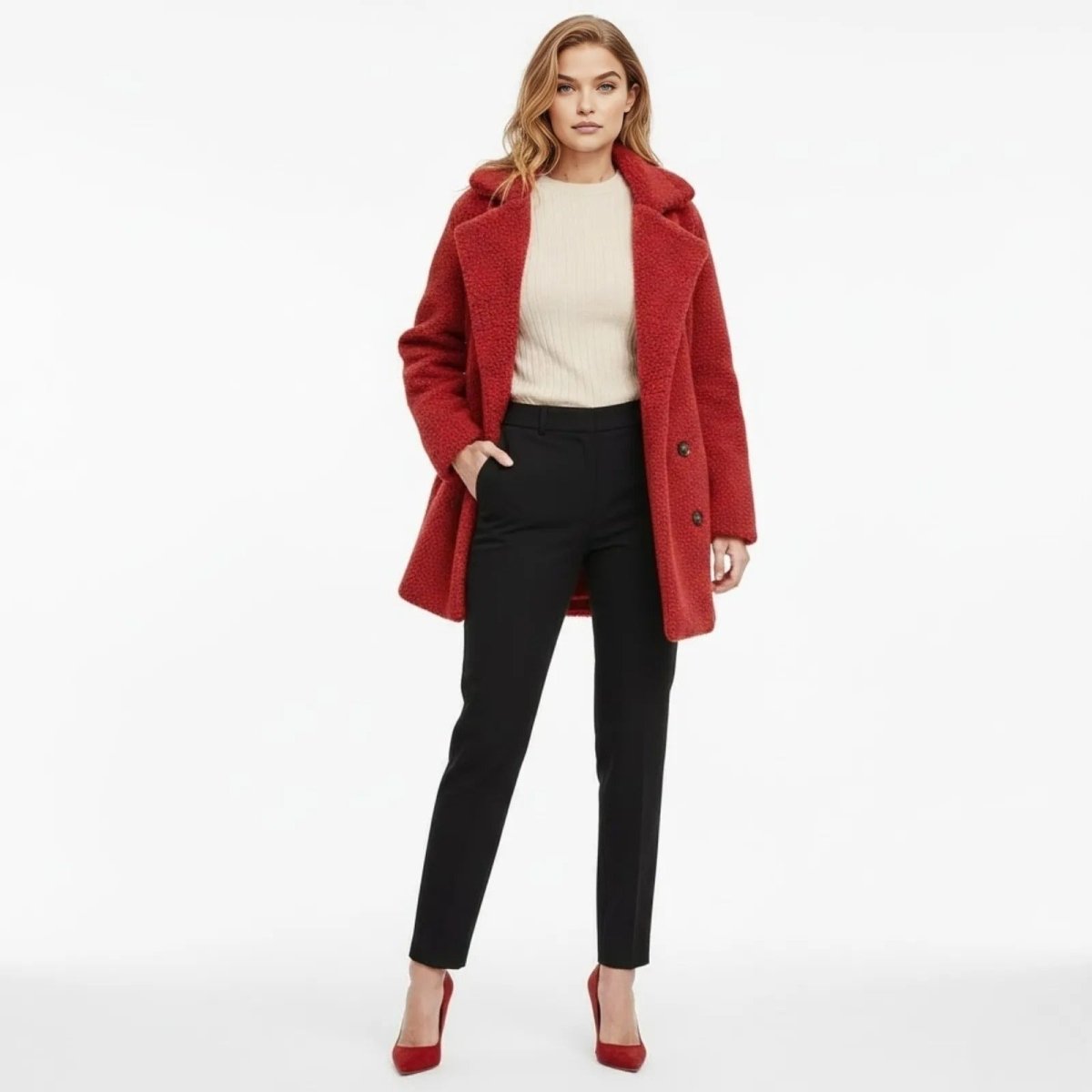 Model wearing the Kouvr Fashion crimson red double-breasted teddy coat, styled with a cream sweater, black tailored trousers, and matching red heels.