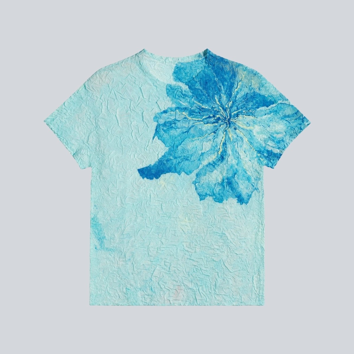 Flat lay clothing view of blue textured short sleeve shirt highlighting the dark blue flower pattern and crinkle fabric