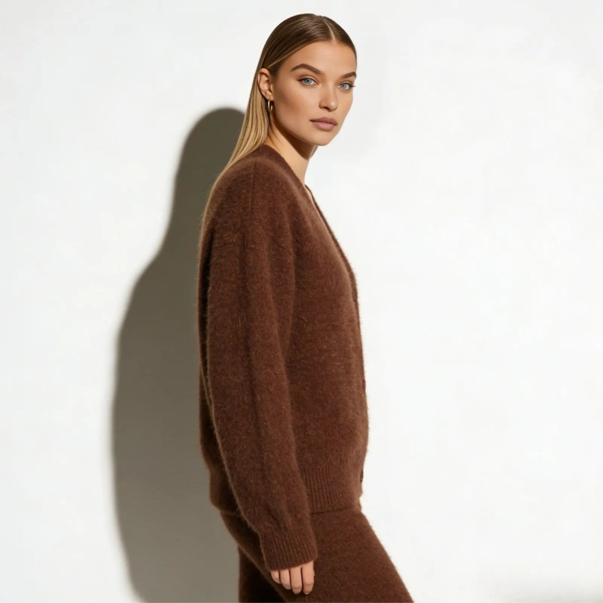 Side profile of a woman wearing a soft, fuzzy brown cardigan from Kouvr, showing its oversized, relaxed fit and sleeve length.