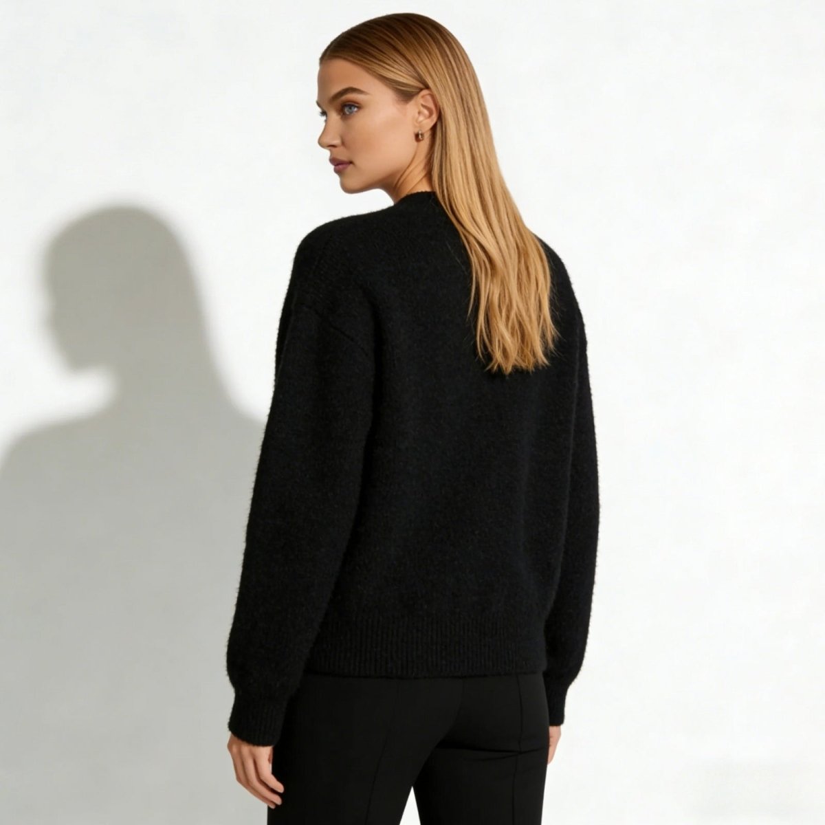 Full back view of the Kouvr Gina black V-neck cardigan on a model, highlighting the seamless construction and oversized silhouette.