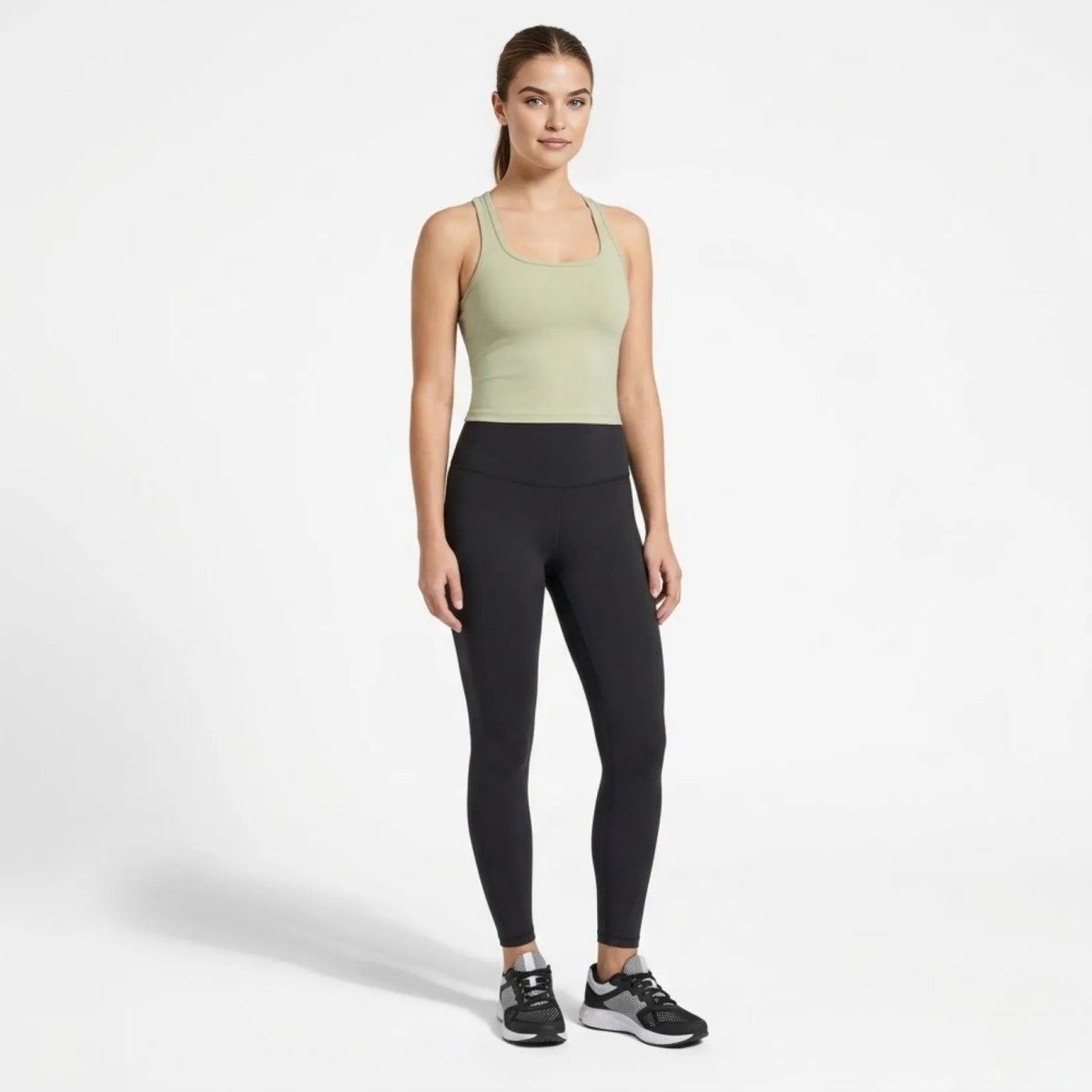 Full body view of model wearing Kouvr affordable luxury green crop top and high waisted black leggings ready for studio workouts.