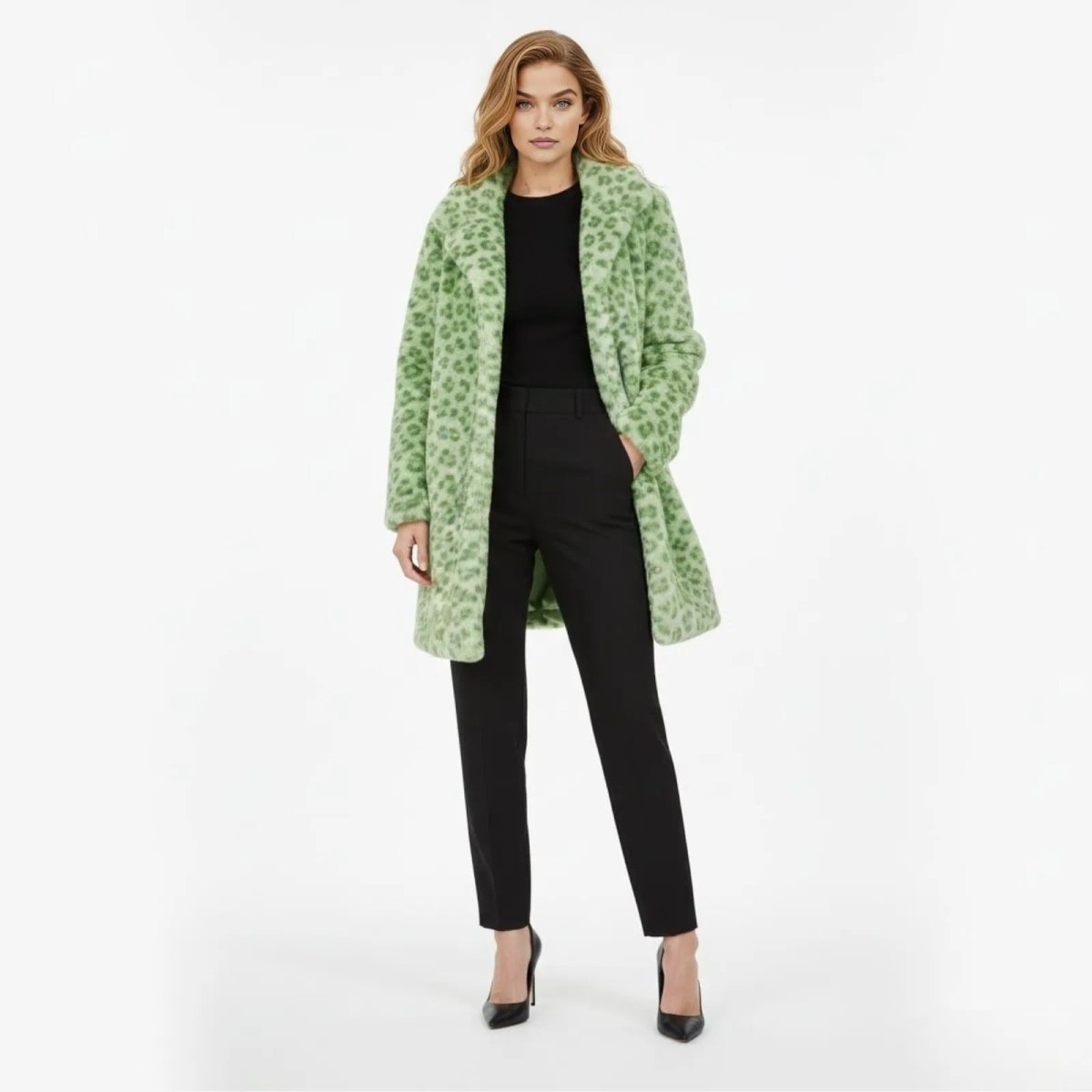Model wearing the Kouvr green leopard print faux fur coat with black trousers and heels, shown from the front against a white background.