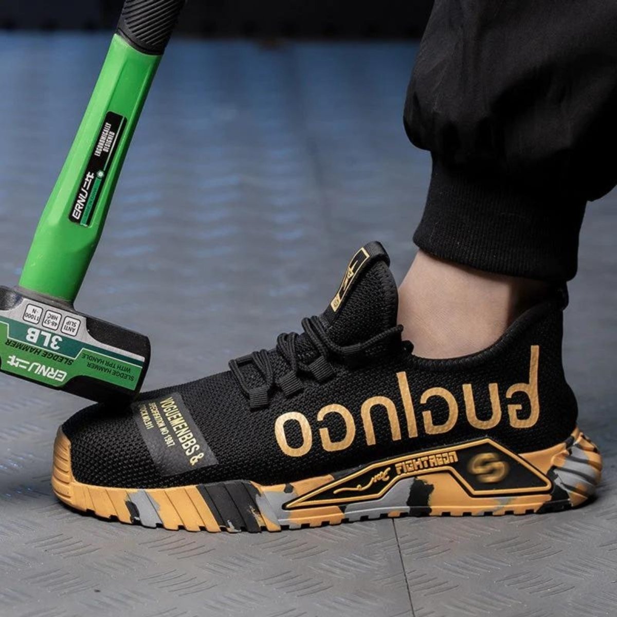 Black and gold Kouvr sneaker with 'Fubu' branding being hammered by a green hammer on a blue floor.