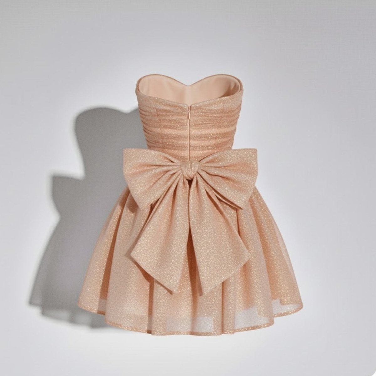 Close-up back product view of the Kouvr Harmoni dress, highlighting the oversized bow and ruched bodice on a hanger.