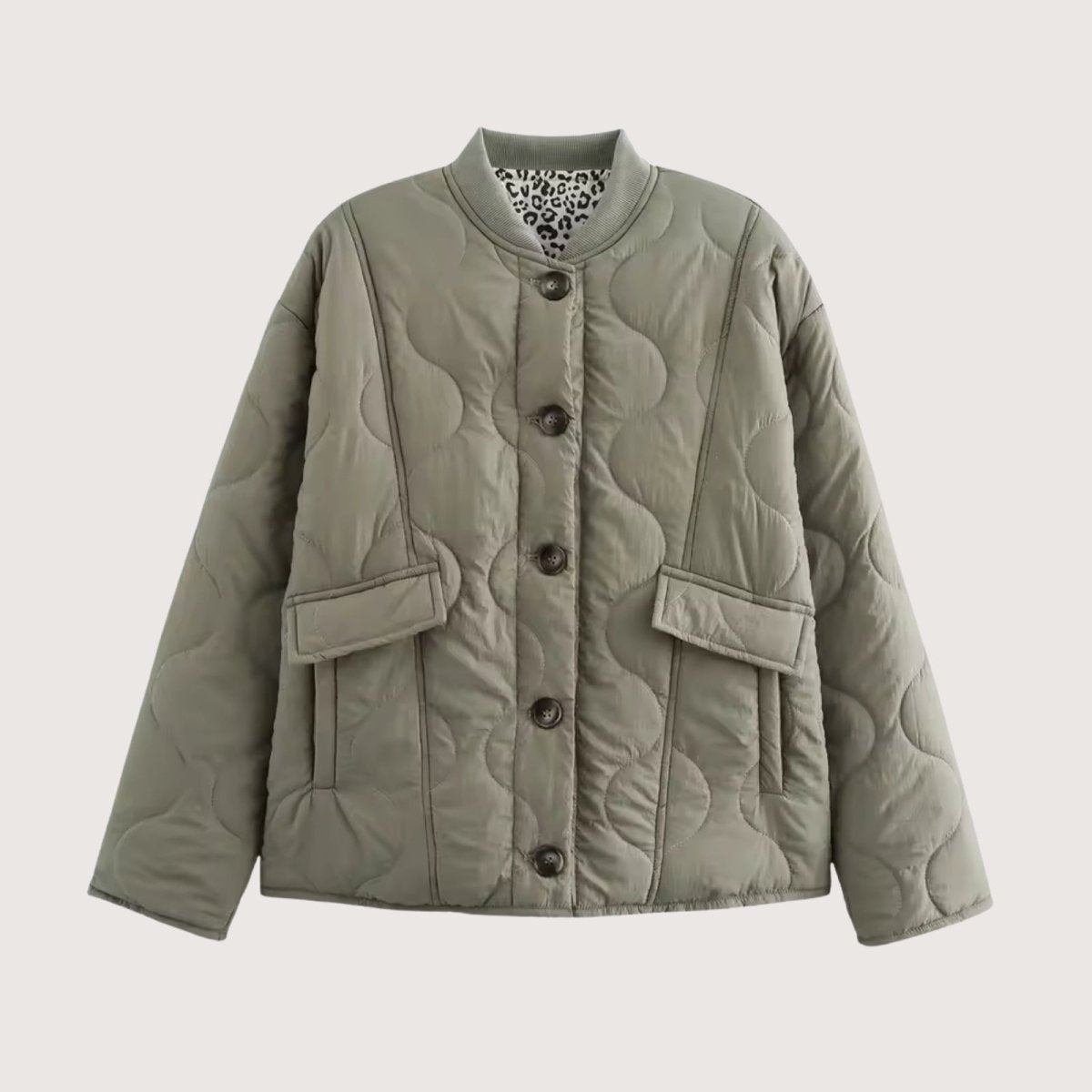 Flat lay product shot of the Kouvr Harmony quilted jacket in sage green, showing the button front, patch pockets, and leopard print interior collar lining.