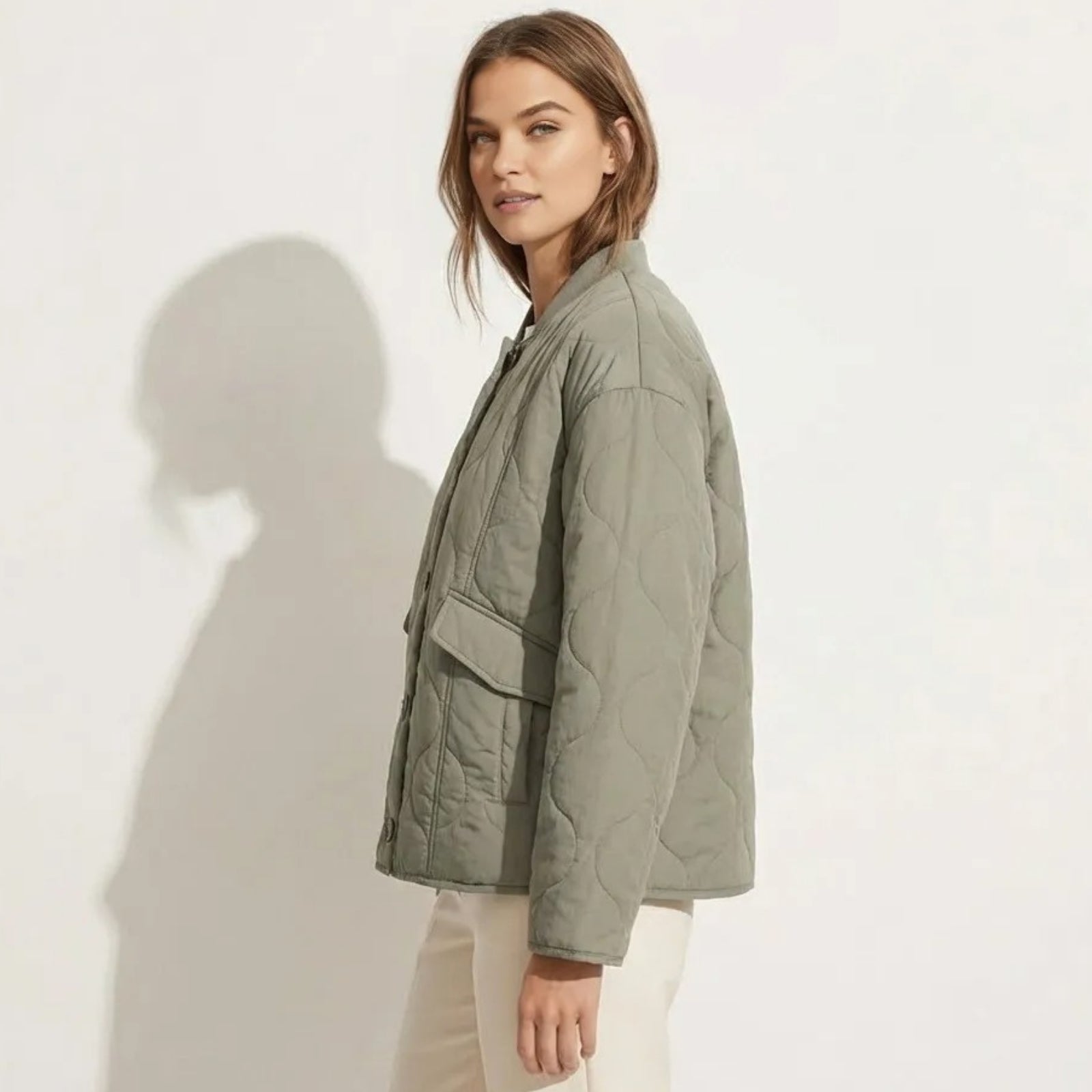 Side profile of a model in the Kouvr Harmony sage green quilted jacket, highlighting the sleeve volume and patch pocket detail.