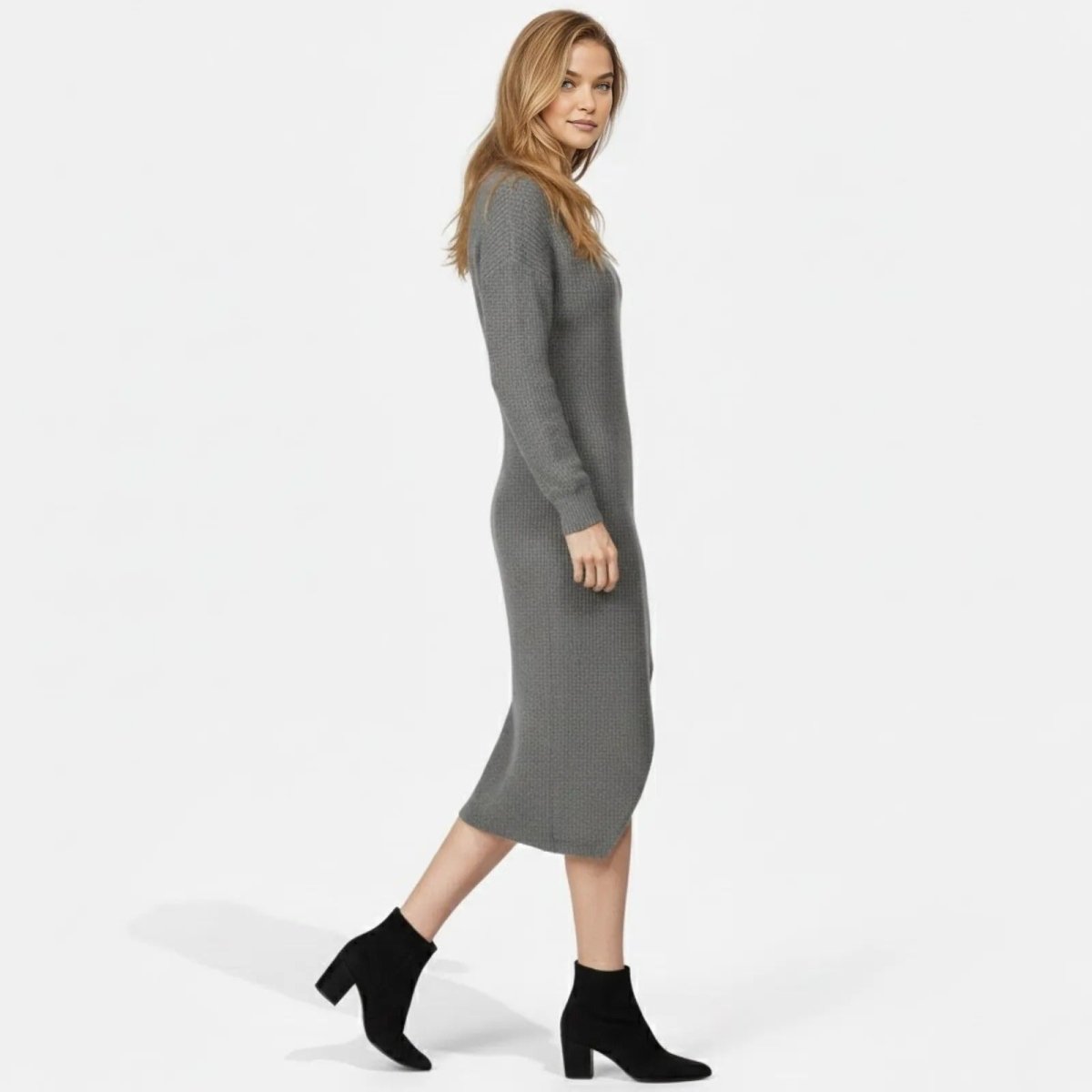 Side profile of a woman walking in a long sleeve grey midi sweater dress, highlighting its length and fit.