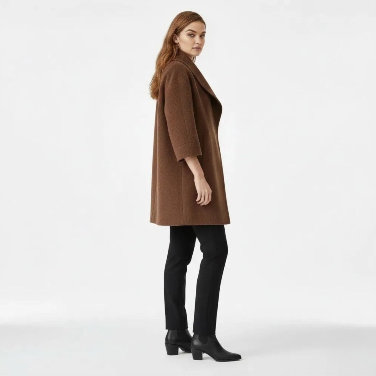 Side profile of a model in the Kouvr Janice oversized coat showing the 3/4 sleeve length and mid-thigh hem.