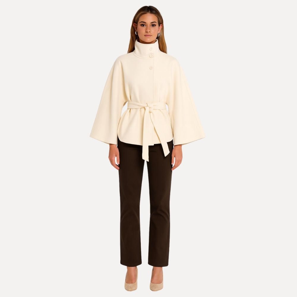 Model wearing the Kouvr Jannah Wool Cape Jacket in White, featuring a high funnel neck and tie-waist belt." For the back view