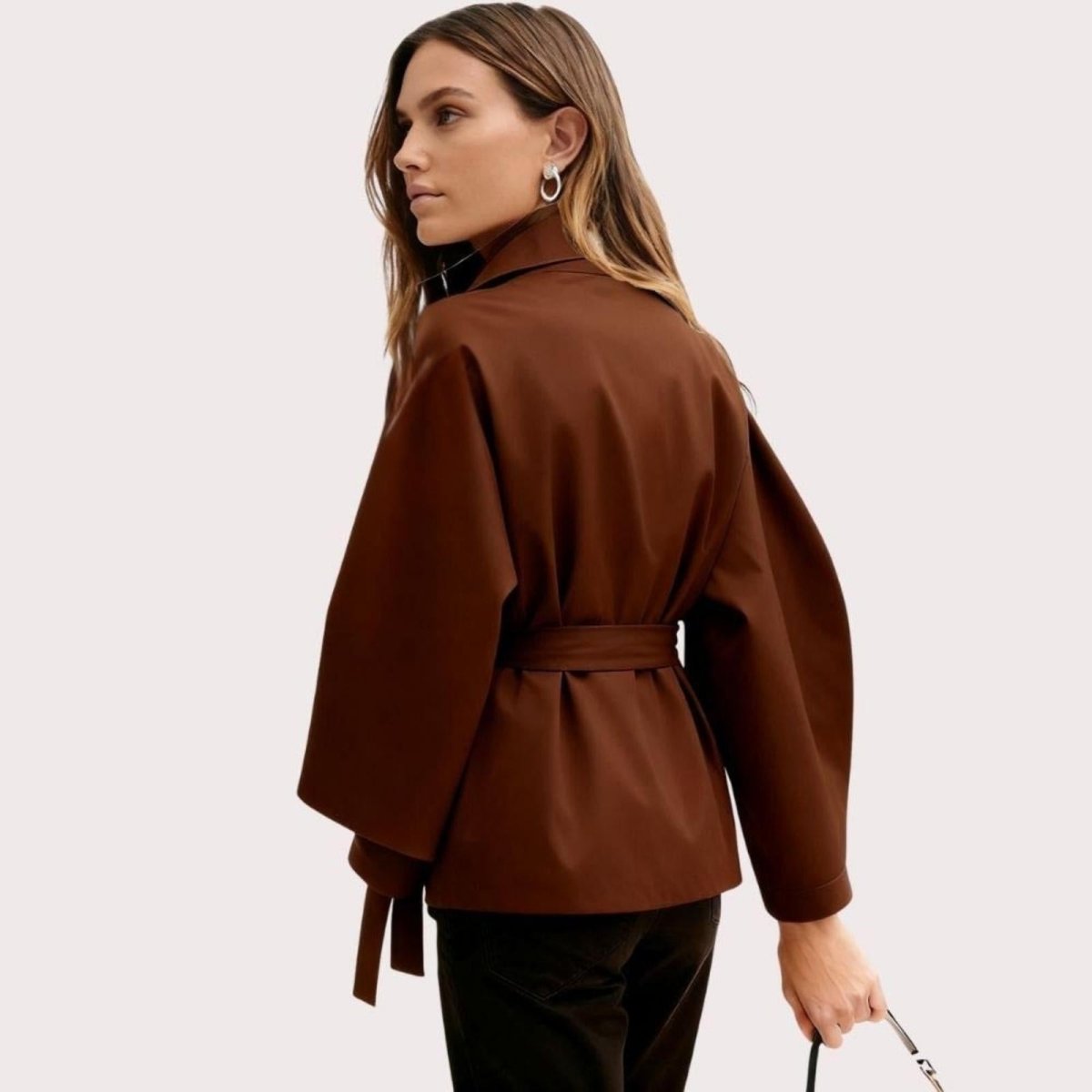 Model from the back wearing the Kouvr Jaye Belted Cape Jacket in Brown, showcasing the wide sleeves and tie-waist detail