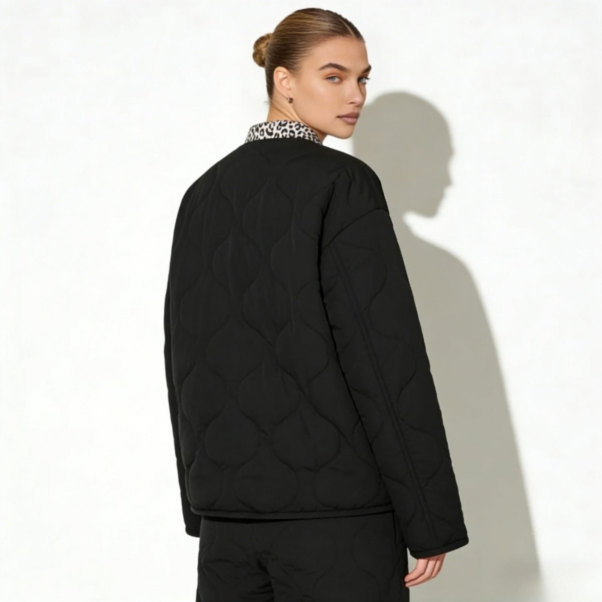 Back view of a model in the Kouvr Jennalyn black quilted jacket, highlighting the signature onion-quilt pattern and the contrast leopard print collar.
