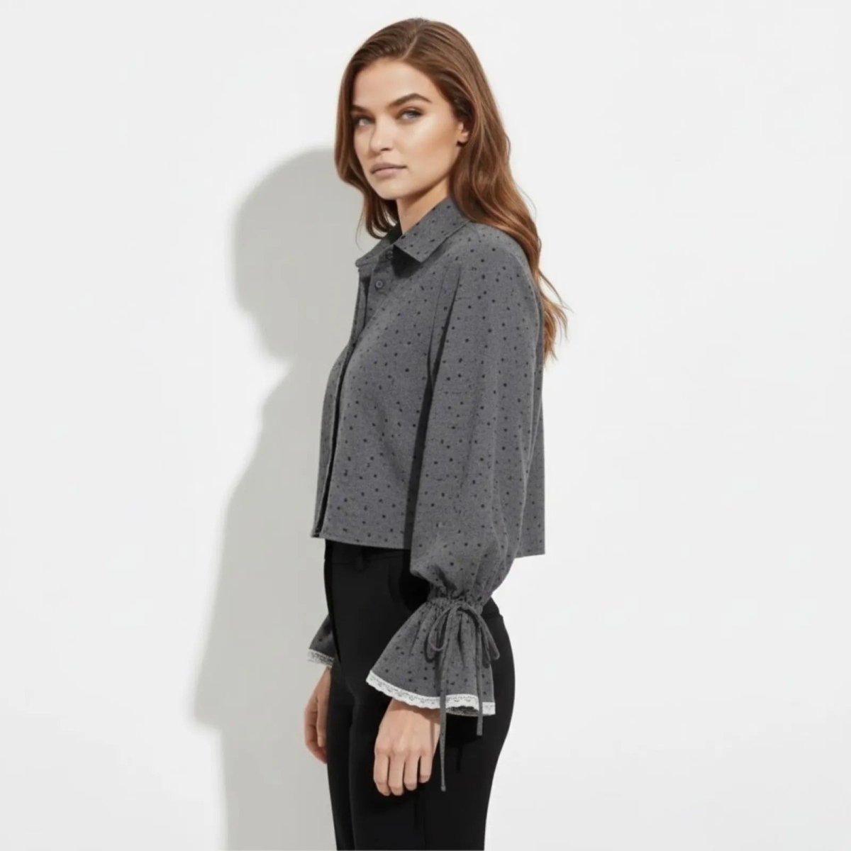 Side profile of a model wearing the Kouvr Kara gray dotted blouse, highlighting the cropped length and the silhouette of the balloon sleeves.