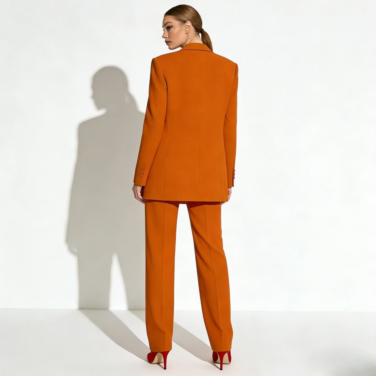 Back view of the Kouvr Fashion kate orange suit, highlighting the expert tailoring of the single-breasted blazer and the fit of the wide-leg pants.