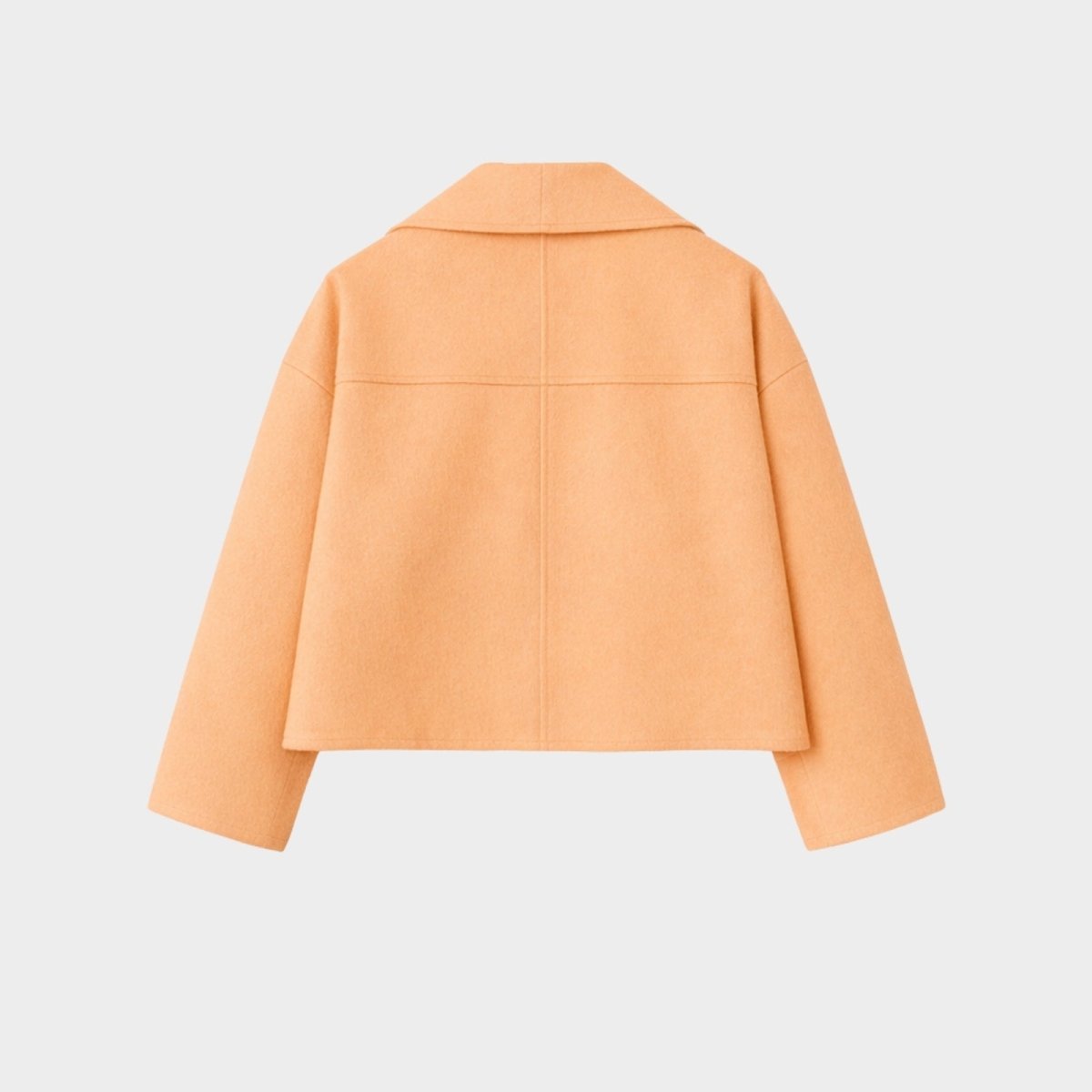Back view of a model wearing the relaxed-fit Kouvr Katherine cropped wool coat in peach to show how the garment drapes.
