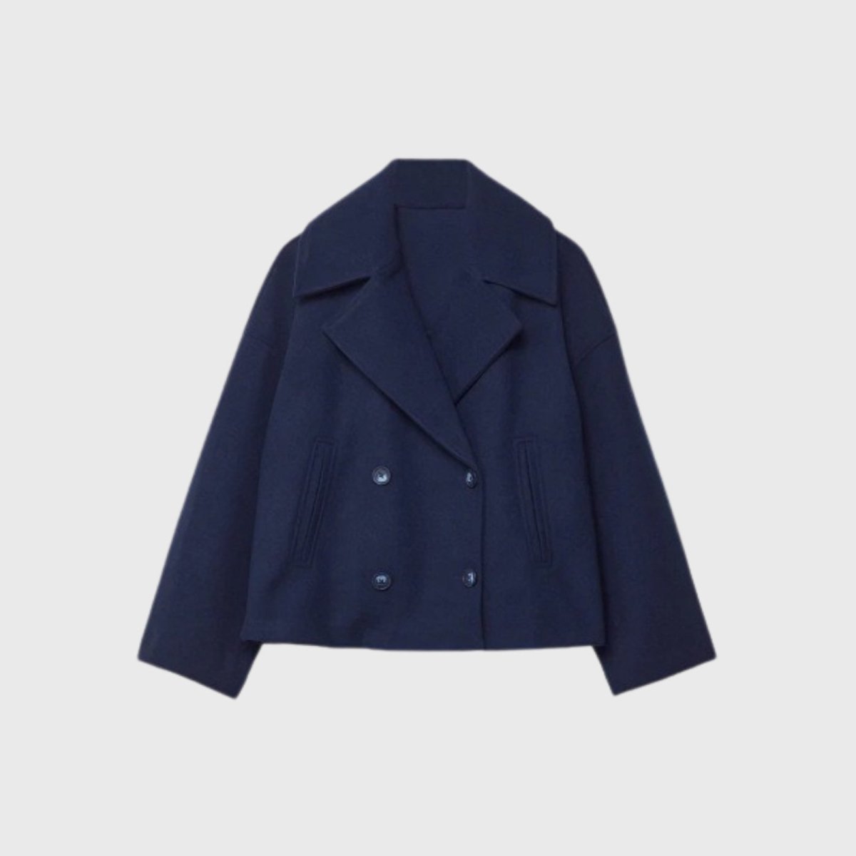 Studio flatlay of the Kouvr Katherine navy cropped wool peacoat, detailing the wide lapels and double-breasted corozo button closure.