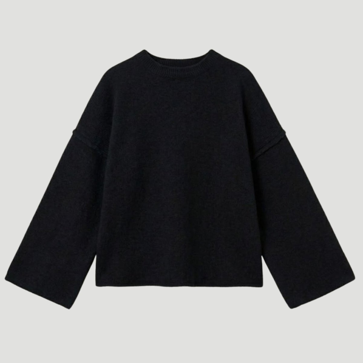 Flat lay of a black oversized crewneck sweater with wide bell sleeves and external seam details, made from a luxury wool-cashmere blend.