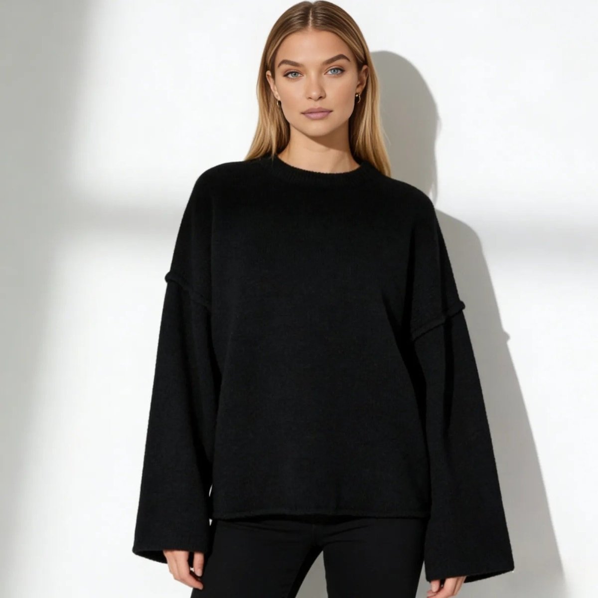 Model wearing the Kouvr Krystal oversized black sweater with wide bell sleeves, showcasing its slouchy, minimalist fit.