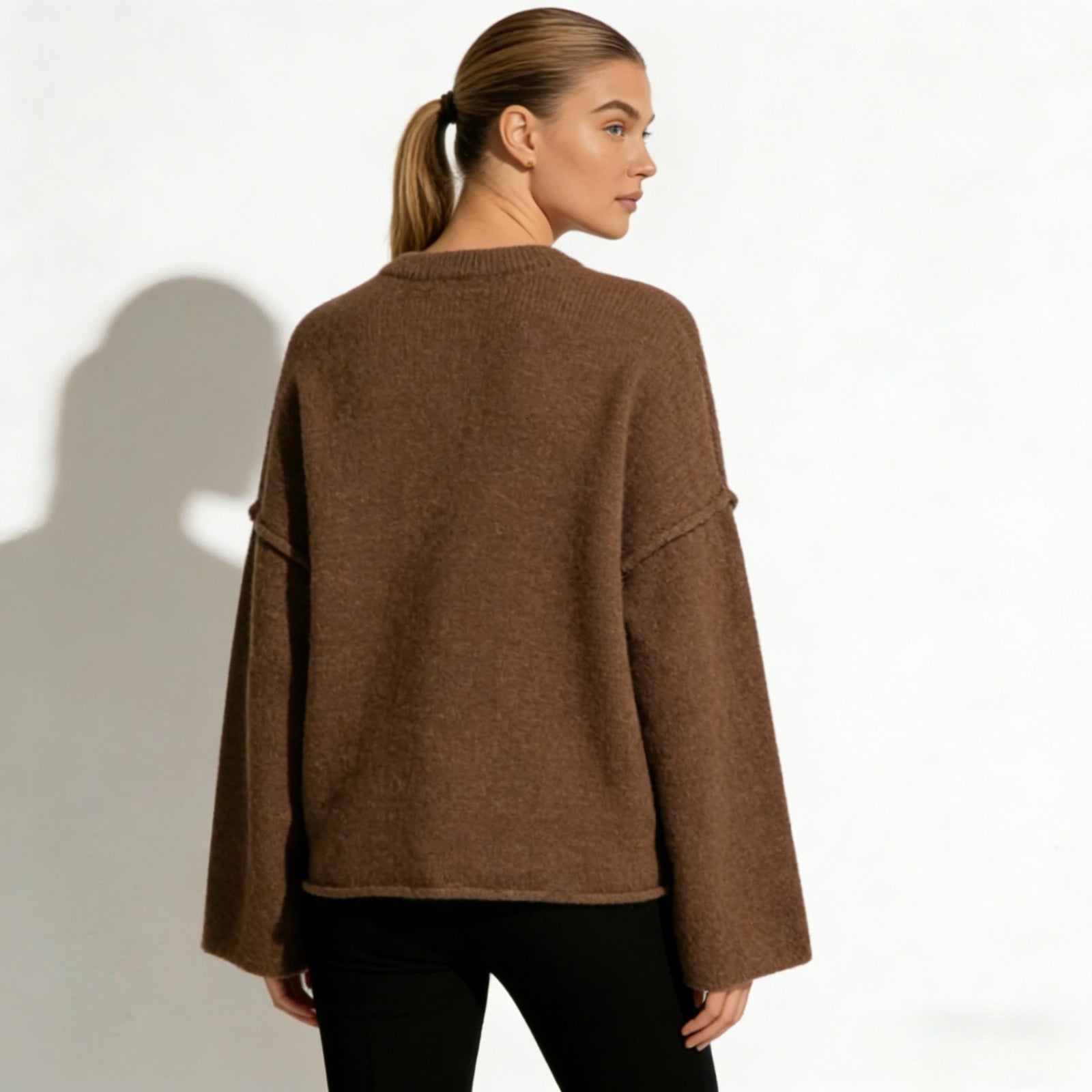 Back view of the Kouvr Krystal oversized knit sweater, highlighting its boxy silhouette and clean lines in a warm brown hue.
