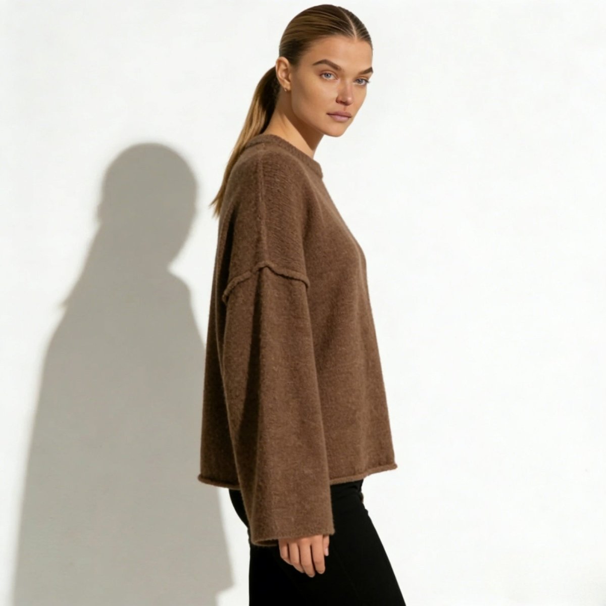 Side profile of the brown alpaca blend sweater showcasing the dramatic width of the bell sleeve and the dropped shoulder seam detail.