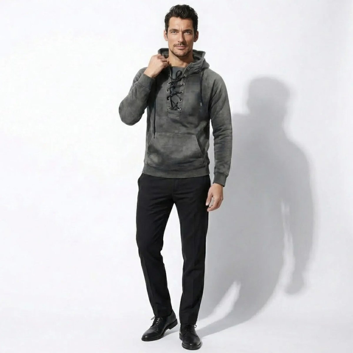 Male model wearing the Kouvr grey lace-up cannon hoodie, facing forward against a white background.