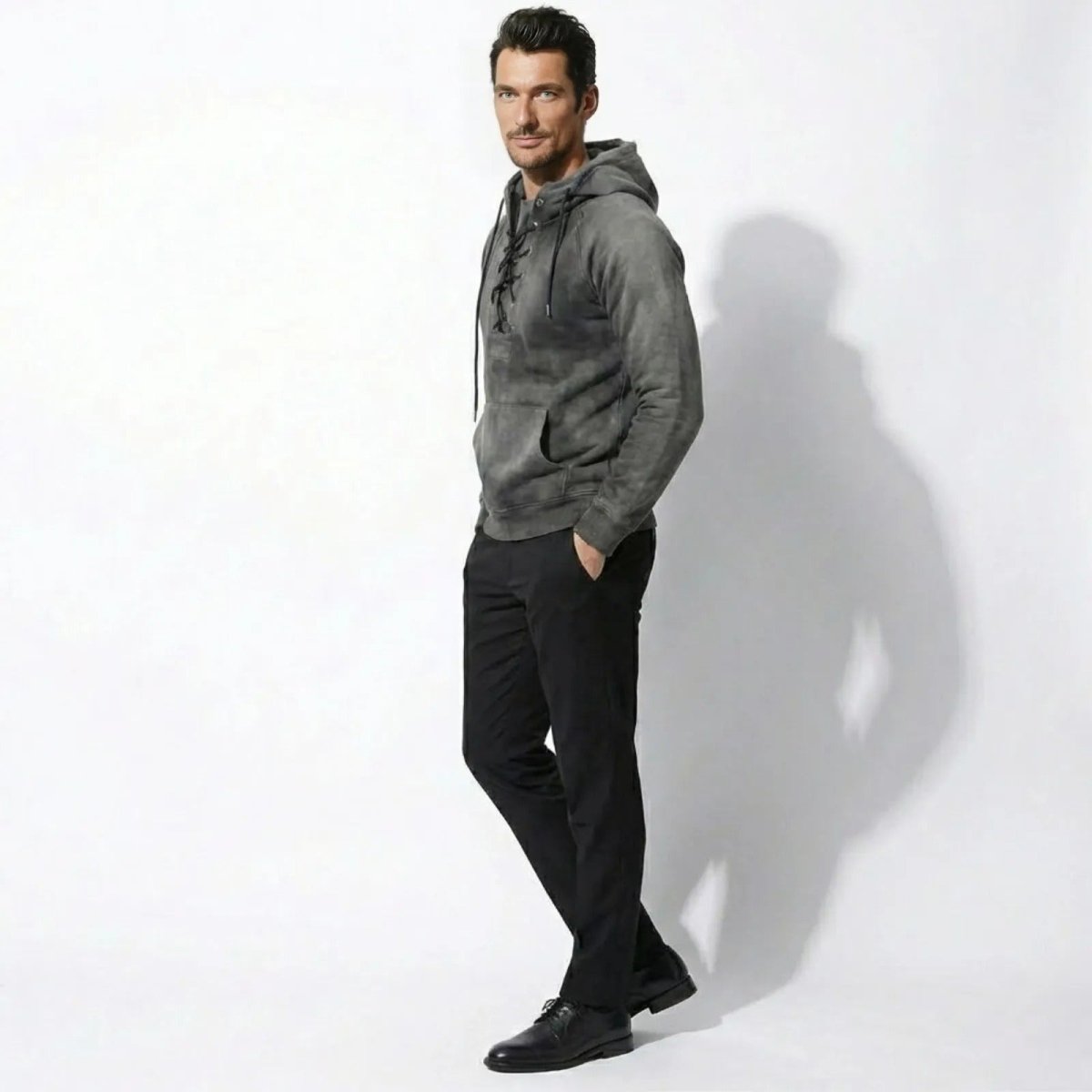 Male model in a side profile view wearing the Kouvr grey lace-up hoodie with hands in pocket.
