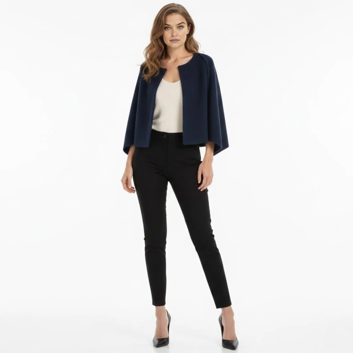 Woman wearing the Kouvr Laverne structured navy blue wool cape jacket, styled with a white top and black tailored trousers, front view.