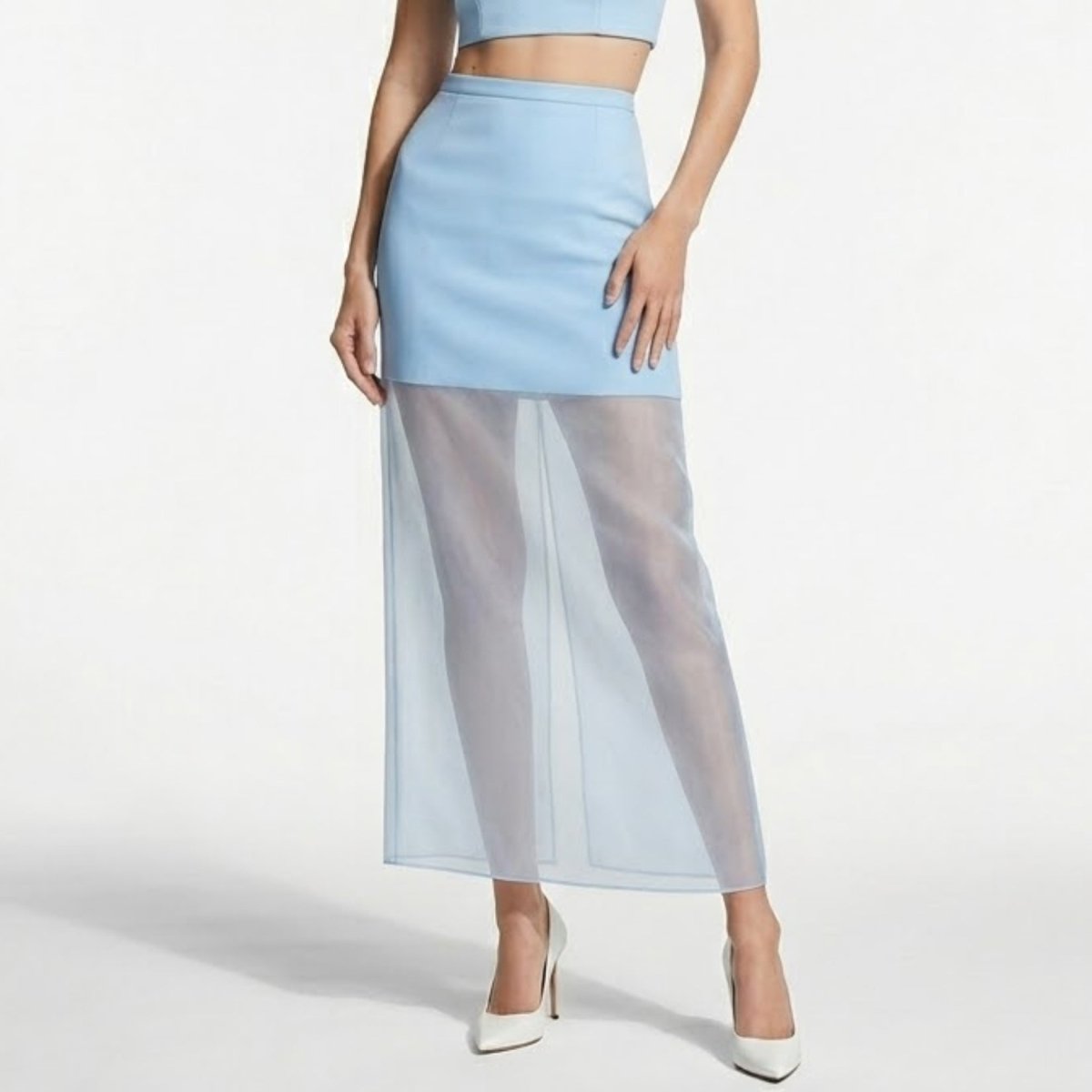 Woman wearing a light blue high waisted midi skirt featuring a tailored mini top and sheer organza maxi overlay for affordable luxury evening wear.