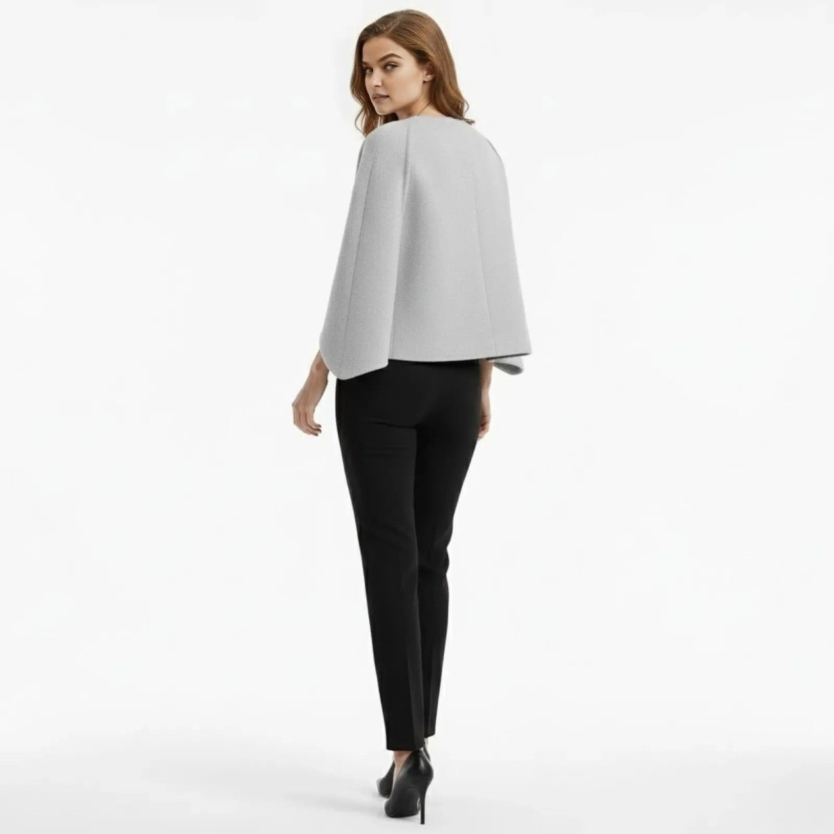 Back view of a model in the Kouvr light grey structured cape jacket, showcasing the minimalist design.