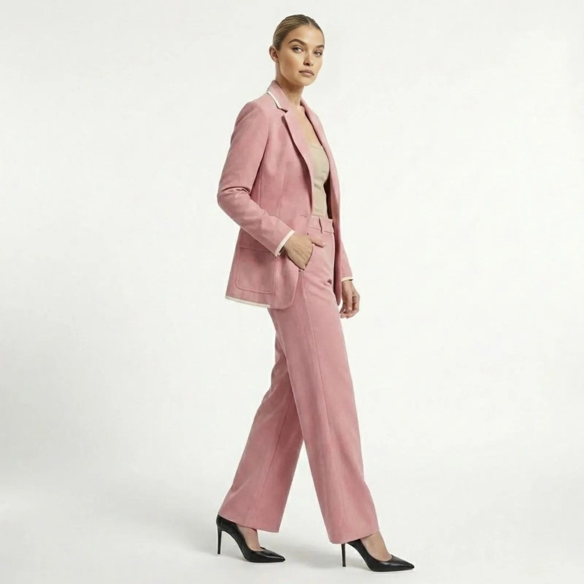 Side profile of a model walking in a dusty rose two-piece suit set, showcasing the relaxed fit of the blazer and the fluid drape of the wide-leg pants.