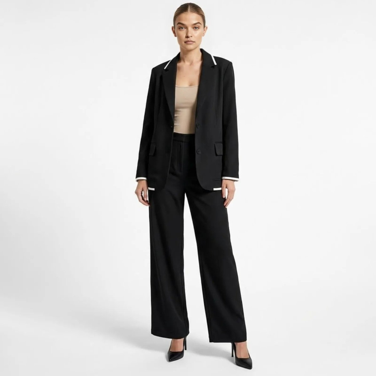 Model wearing the Kouvr Lucia Set Power Suit in black with white contrast piping, standing front-on in a professional two-piece set with wide-leg trousers.