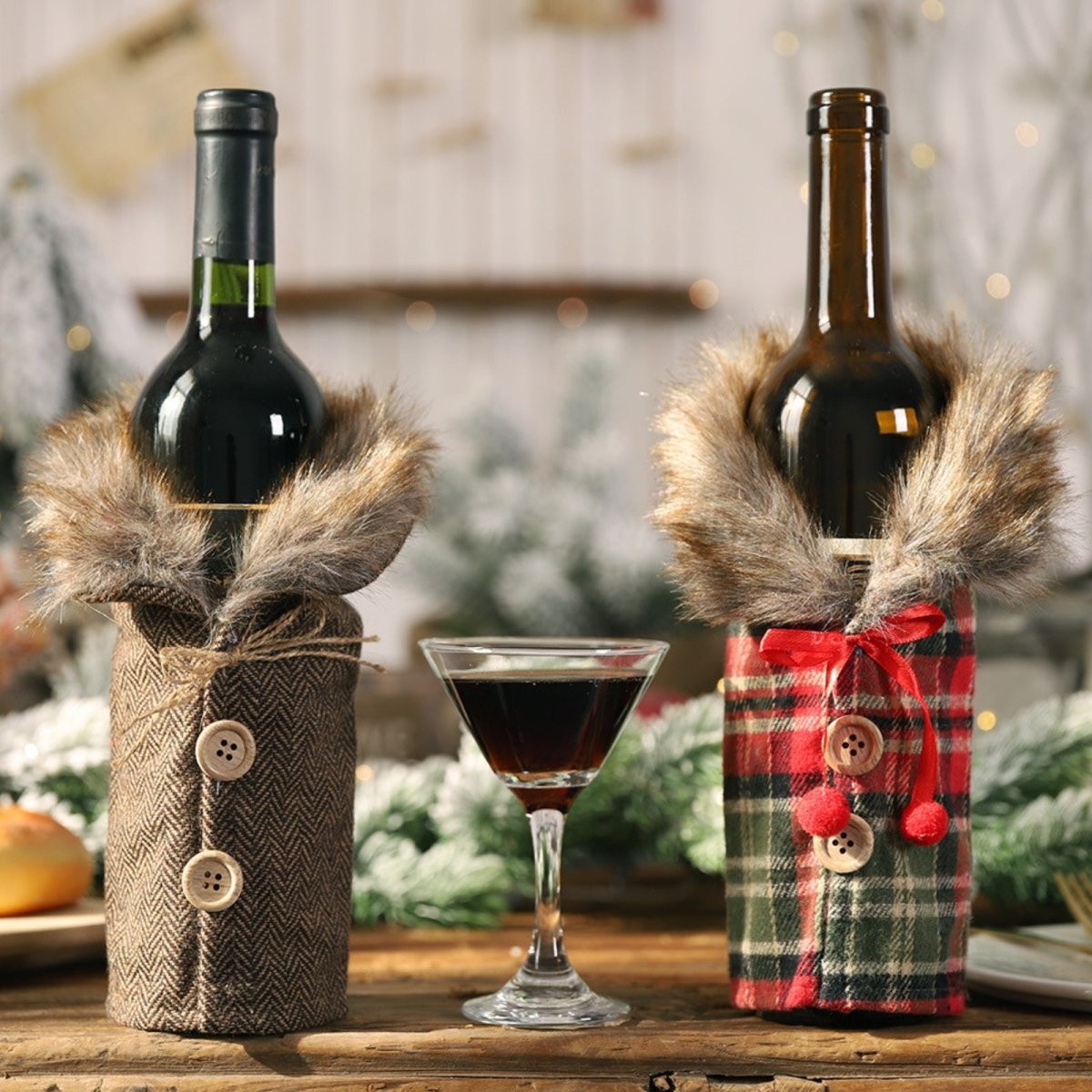 Front view of two wine bottles in decorative fur-collared coats as a centerpiece for a Christmas dinner table, with a wine glass between them.
