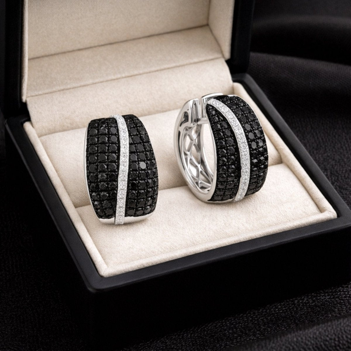 Kouvr's black and white diamond huggie earrings presented in a luxury black jewelry box, highlighting them as a premium gift.