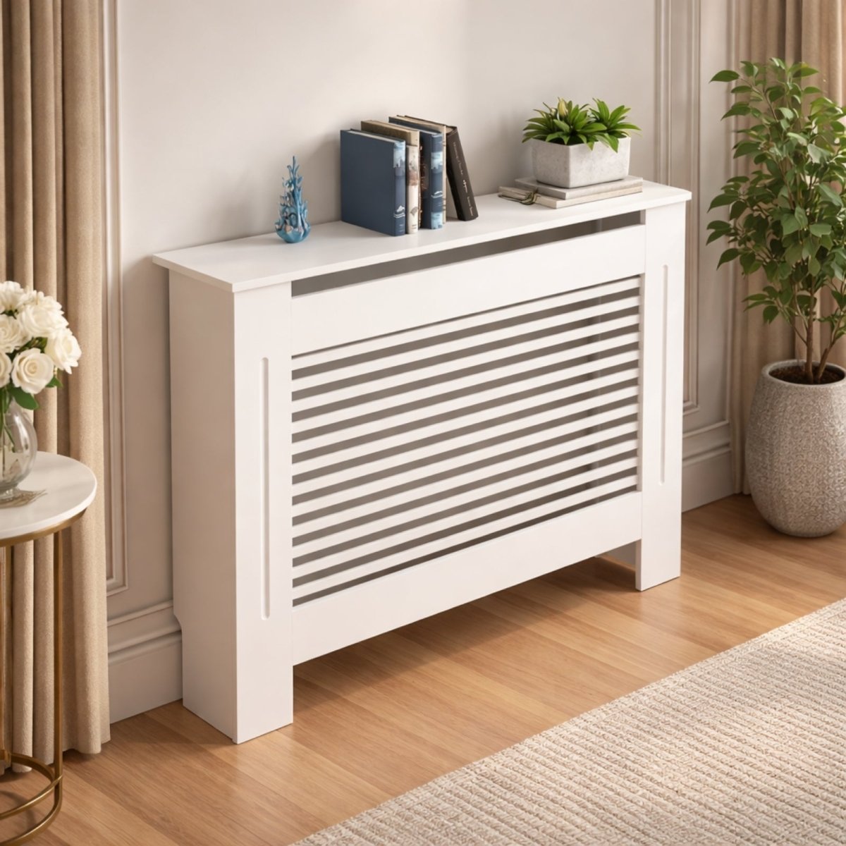A medium-sized white radiator cover with a clean, modern design, placed against a white wall next to a large potted plant and a small side table.