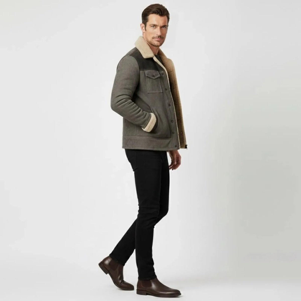 Male model in a side profile walking pose wearing the Kouvr grey suede aviator jacket, showcasing its tailored fit and shearling-lined collar.