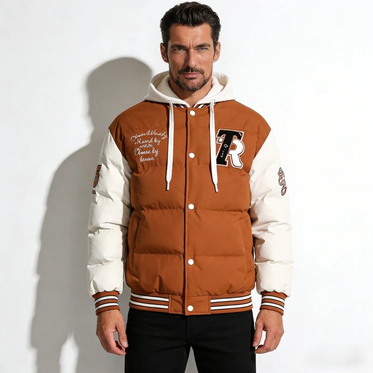 Model wearing the Kouvr men's cognac camel hooded puffer varsity jacket, showing the 'R' chenille patch and snap button front