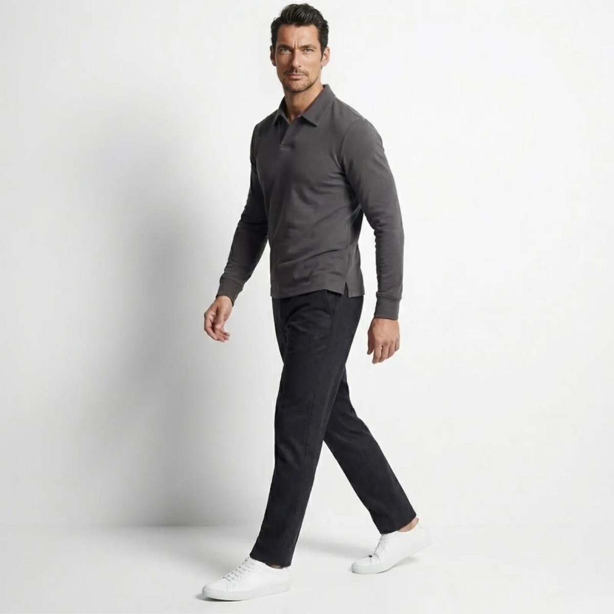 Side profile of a man walking while wearing the Kouvr charcoal grey long sleeve polo, demonstrating the shirt's fit and drape.