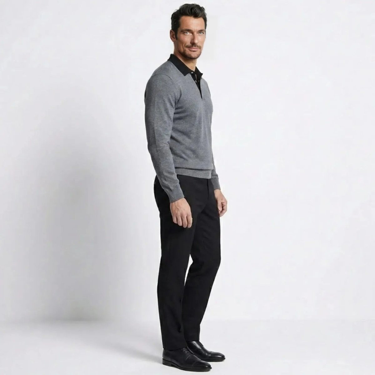 Side profile of a man wearing the Kouvr heather dark grey and black long-sleeve polo sweater, showcasing its tailored fit.