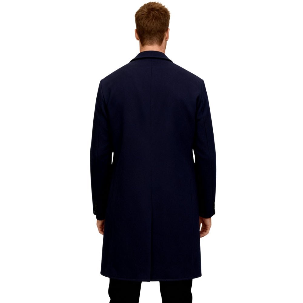 Man wearing a navy blue Kouvr overcoat on a white background