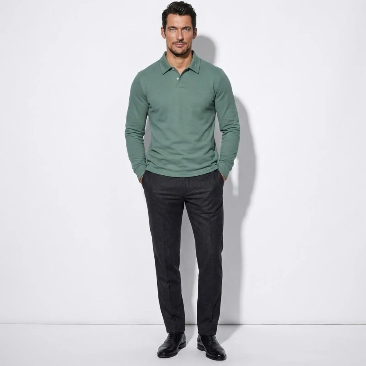 Model wearing the Kouvr men's long sleeve polo in sage green, paired with dark tailored trousers, shown from the front.