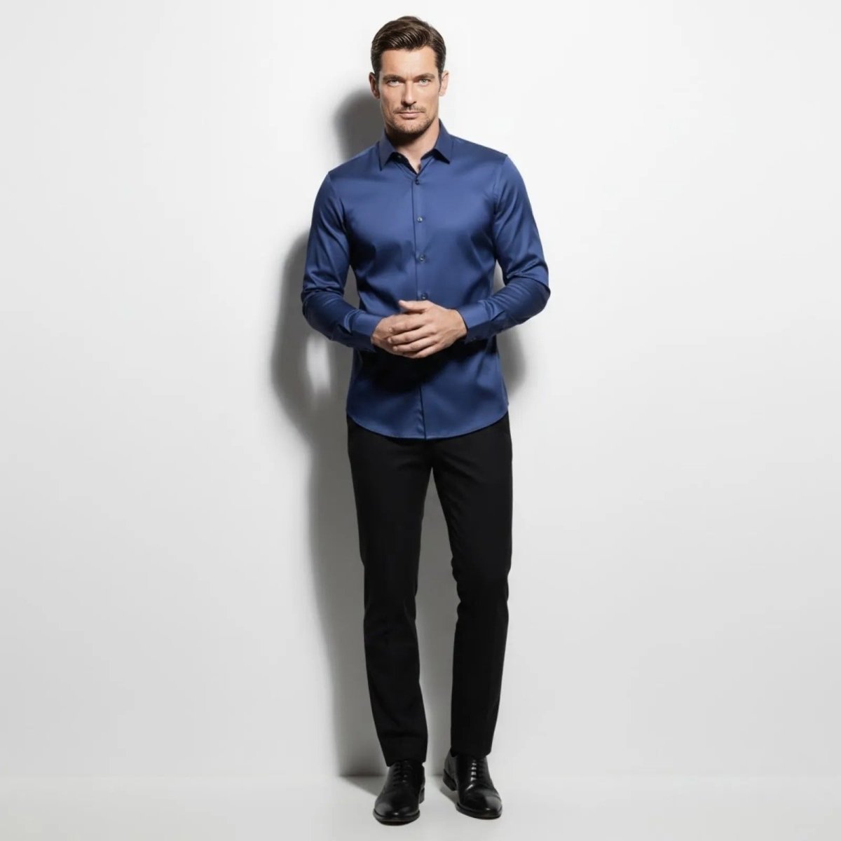 Male model wearing the Kouvr slate navy blue slim fit performance dress shirt, front view, paired with black trousers.