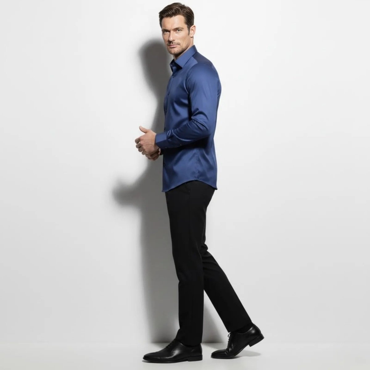 Side profile of a male model in a Kouvr slate navy blue long sleeve performance shirt showcasing the slim athletic fit.