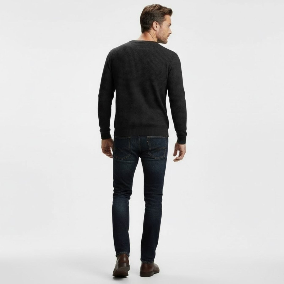 Back view of a male model wearing the Kouvr black waffle-knit sweater, showcasing the garment's fit and texture.
