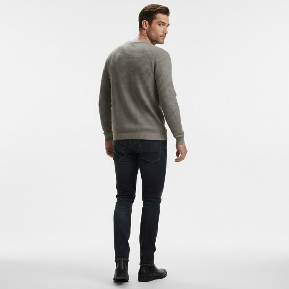 Male model seen from the back wearing the Kouvr grey waffle knit sweater, demonstrating the fit and silhouette from behind.