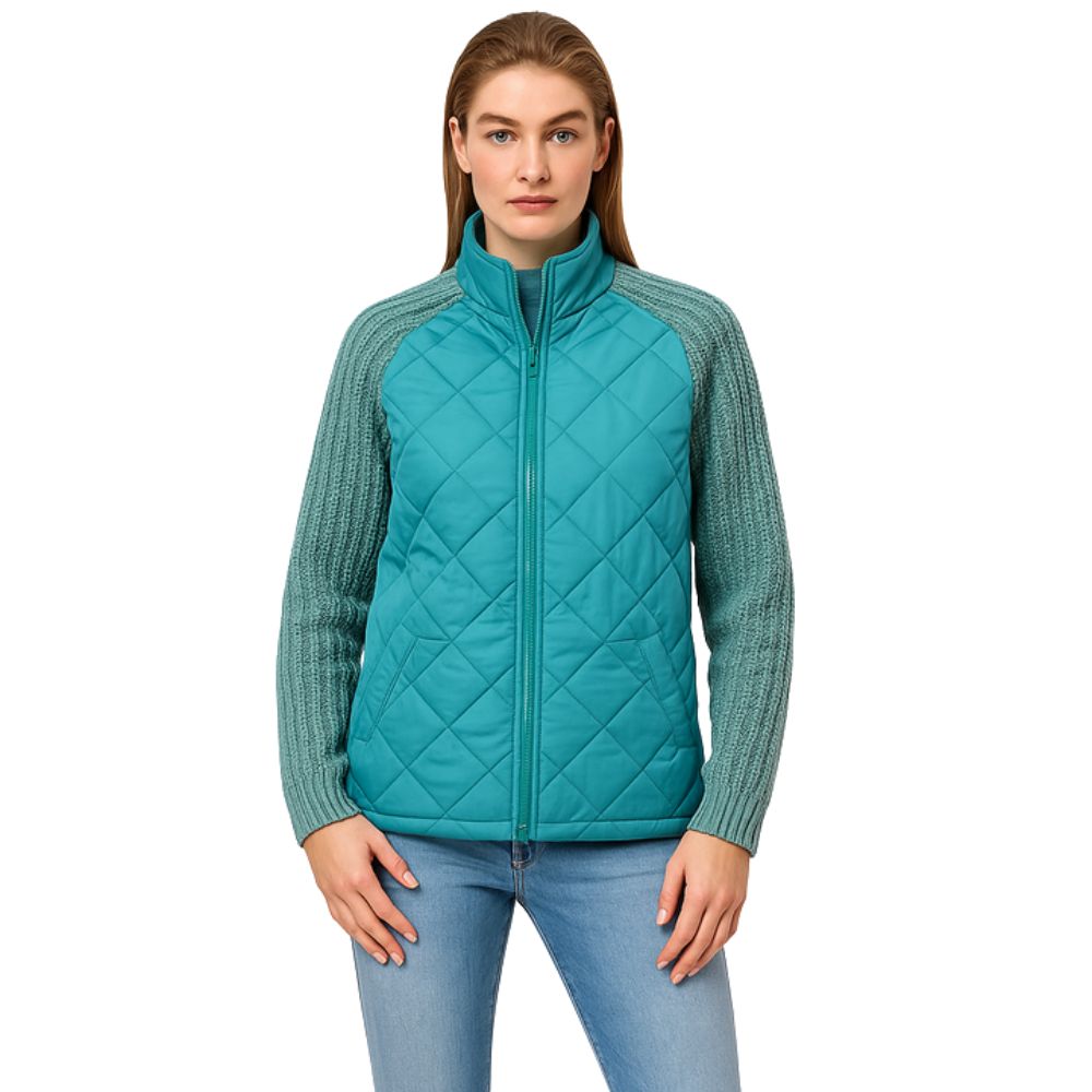 Model wearing the Kouvr Mika Hybrid Bomber Jacket in Aegean Teal, featuring cable-knit sleeves and a diamond-quilted body, paired with light-wash skinny jeans